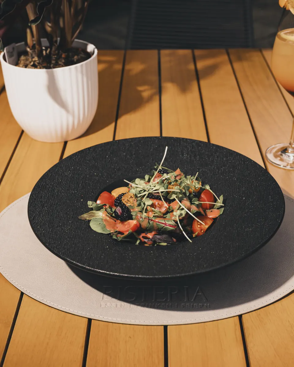 Sommersalat mit Sprossen in dunkler Schale auf dem Terrassentisch